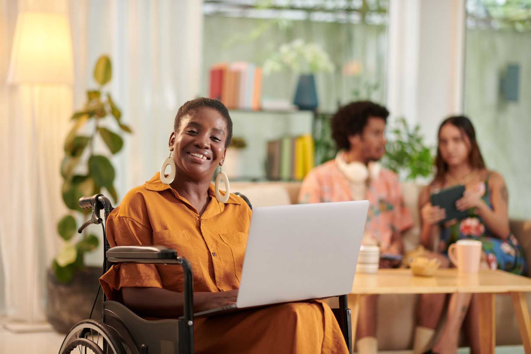 A smiling young woman in a wheelchair working on a laptop